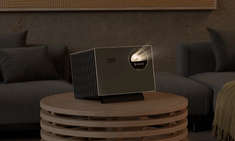 A projector is placed on a small round table, projecting an image; beams of light can be seen.